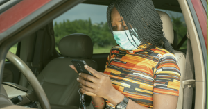 Woman in car on phone wearing a face mask